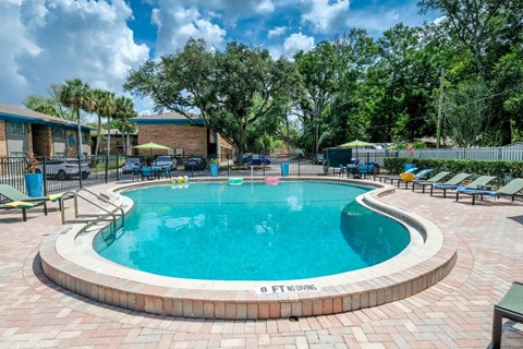 Community pool at the Watermarc luxury Apartments in Lakeland, Fl surrounded by green hedges and iron fencing with gate to parking lot.